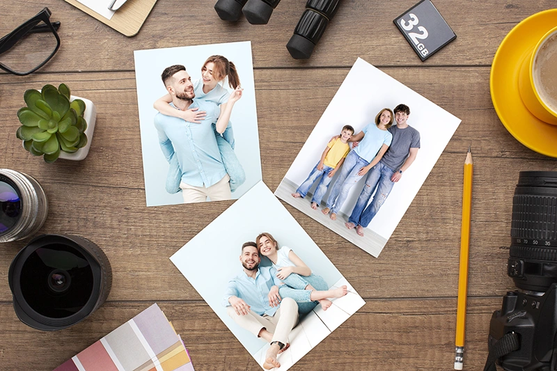 Фотографии фотографии размером А5 на деревянном столе рядом с фотоаппаратом и аксессуарами